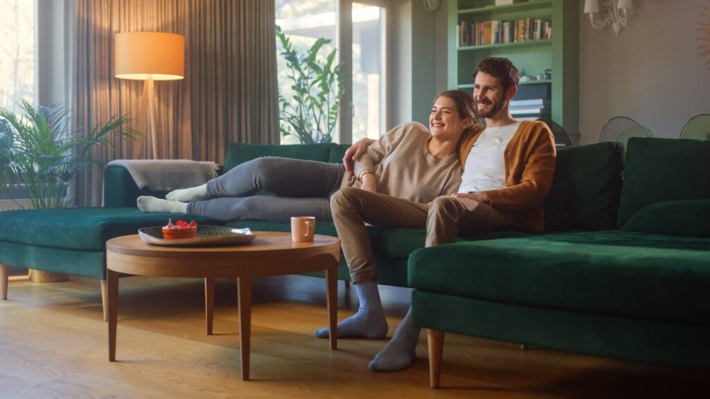 Couple,Watches,Tv,Together,While,Sitting,On,A,Couch,In
