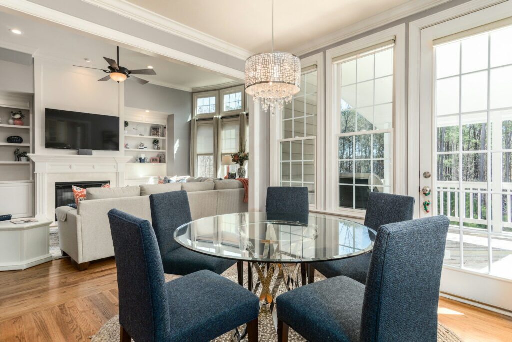 Photo by Douglas Sheppard round clear glass-top table and five gray chairs dining se
