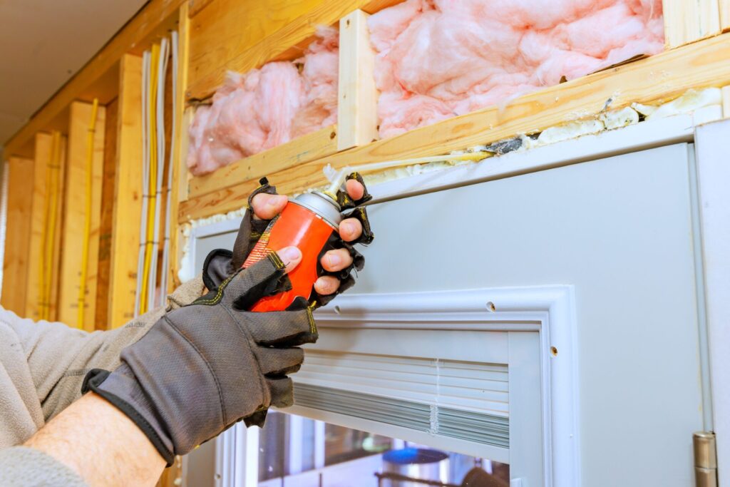 Person,Applies,Weatherproofing,Foam,Spray,Around,Door,Frame,During,Home