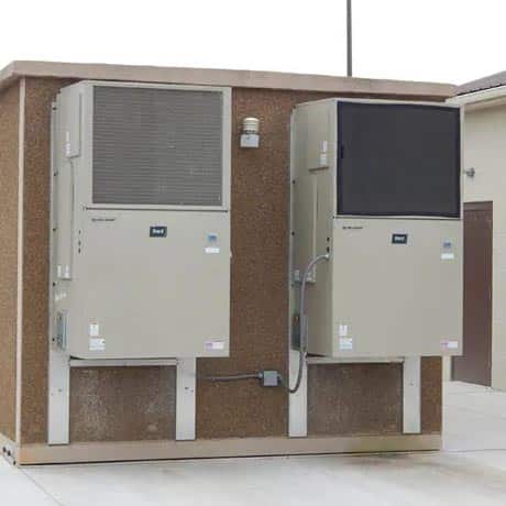 Two-barred wall-mount air conditioning units on the side of an equipment housing