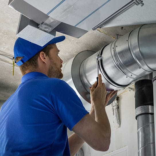 ducts-tech-working-544x544-v1 An HVAC technician working on ceiling mounted ducts