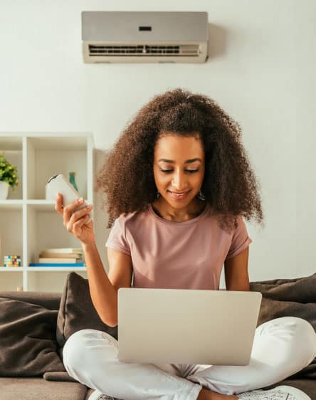 mini-splits-hero-444x562-v1 A woman using a remote to control a mini-split air conditioning system