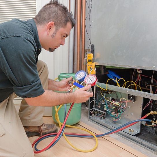 An HVAC service technician repairing a residential air conditioning system inside a house